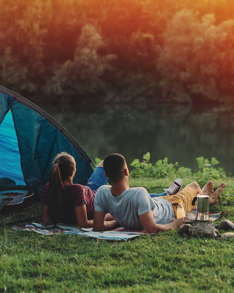 Young couple watching the sunset while on a camping trip