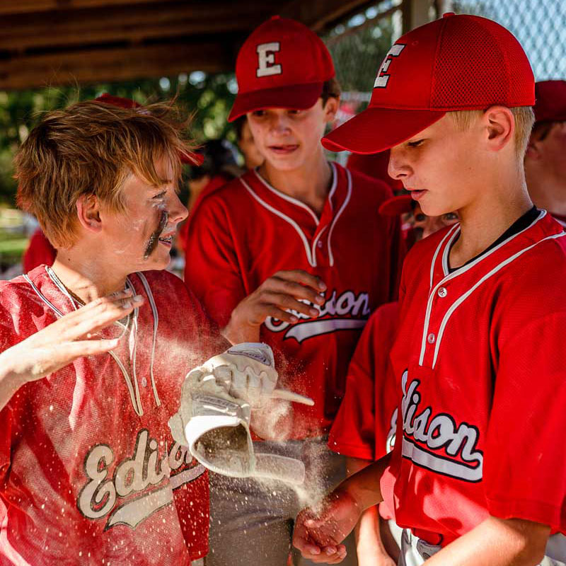 young baseball players talking in the dug out