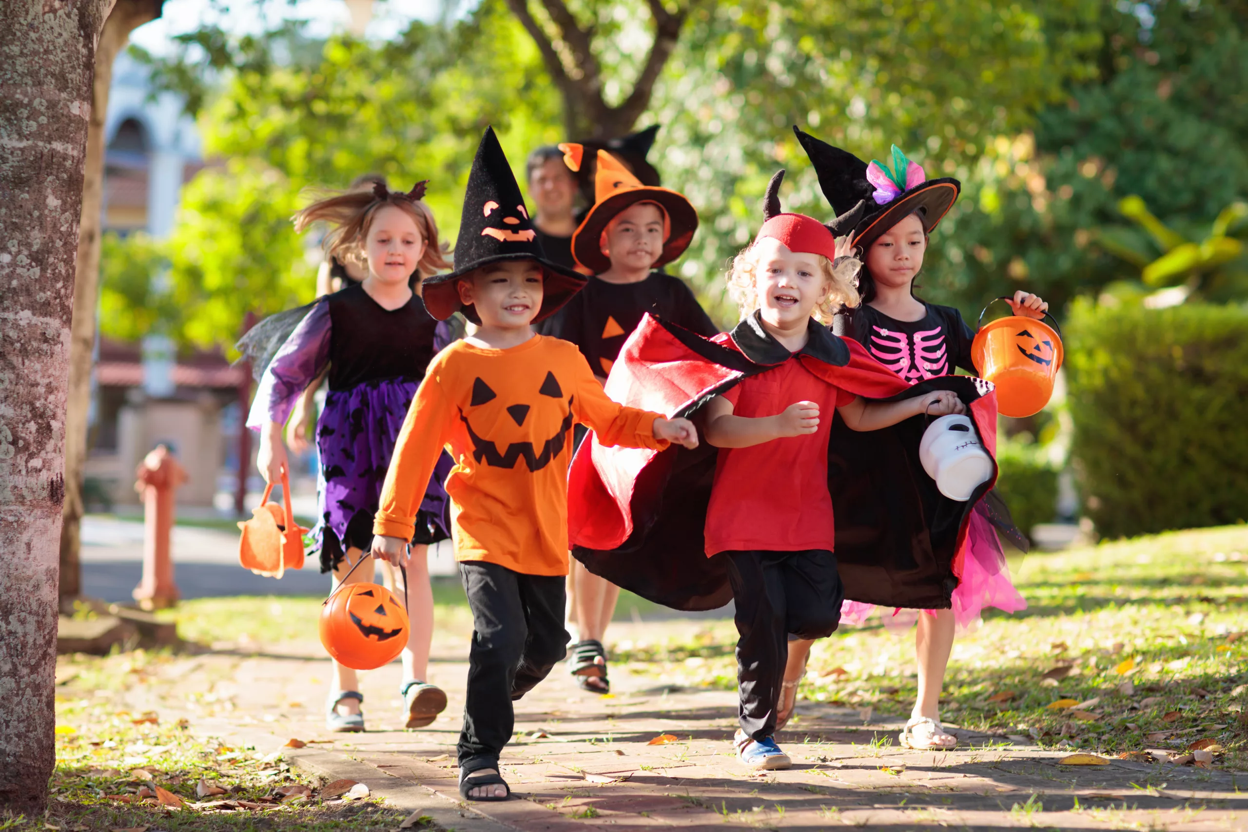 kids treak or treating in their neighborhood wearing Halloween costumes